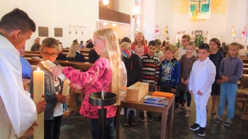  Ein spannender Moment: Die Kesselstädter Kommunionkinder beim Entzünden ihrer Gruppenkerze an der Osterkerze am Taufstein.